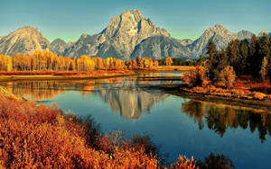Enjoy The Picturesque Autumn Landscape Of A Lake Surrounded By Mountain. Wallpaper