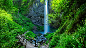 Enjoying A Stunning View Of A Tranquil Waterfall And Bridge Wallpaper