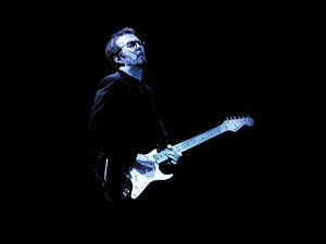 Eric Clapton Illuminated By Blue Stage Lights Wallpaper