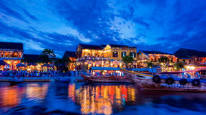 Establishments Along The Riverside At Night Wallpaper