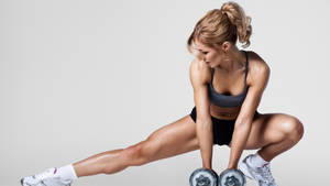 Fit Woman Performing Leg Stretch Wallpaper