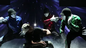 Four Men In Black And Blue Costumes Are Performing On Stage Wallpaper