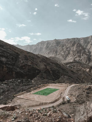 From High Atop The Mountain Range, Get A Glimpse Of A Football Stadium Below Wallpaper