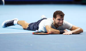 Grigor Dimitrov Laying On Tennis Court Wallpaper