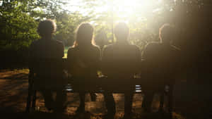 Group Of Friends Sitting On Bench Wallpaper