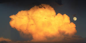 Half-lit Moon Rising Above Dark Clouds Wallpaper