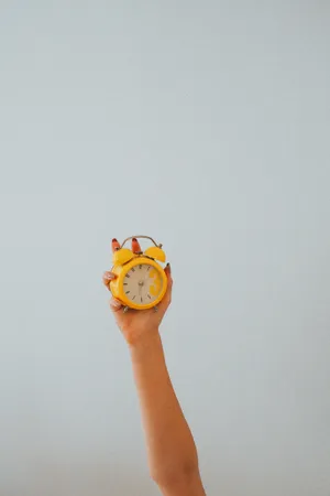 Hand Holding Yellow Alarm Clock Wallpaper