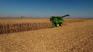 Hardworking Farmer Operating Wheat Thresher Wallpaper