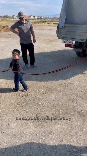 Hasbulla Triumphantly Holding A Ribbon In Front Of Truck Wallpaper