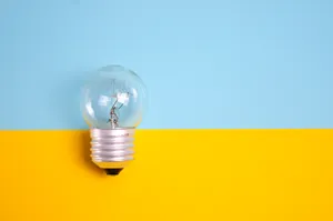 Illuminated Light Bulb Against Bright Background Wallpaper