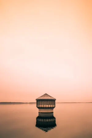 Image A Lake Cottage Atop The Serene Glassy Waters Wallpaper