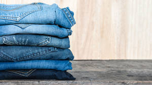 Jeans Stacked On A Wooden Platform Wallpaper