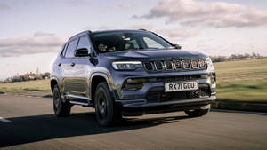 Jeep Compass On The Road Under Clouds Wallpaper