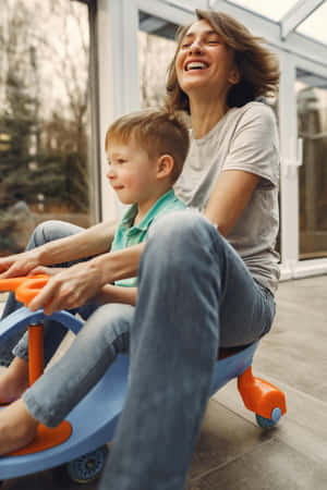 Joyful Moments With Child On Toy Car Wallpaper