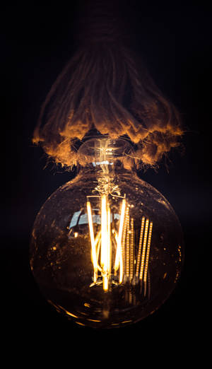 Light Bulb Energy-efficiently Glows In A Dim Room. Wallpaper