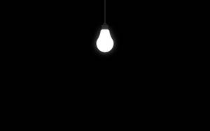 Light Bulb In Solid Black Room Wallpaper