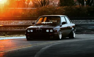 Luxurious Ride: Black Bmw Against A Dramatic Sky Wallpaper