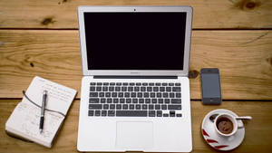 Macbook Air On Wooden Table Wallpaper