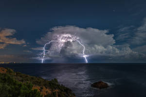 Majestic 4k Sky Showcasing Starry Night And Ocean Lightning Wallpaper