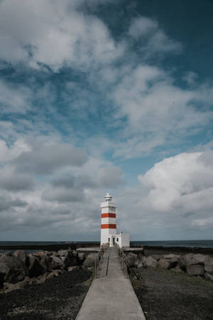 Majestic Lighthouse Under Gray Cloudy Skies Wallpaper