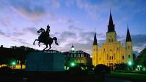 Majestic View Of St. Louis Cathedral With A Statue In The French Quarter Wallpaper