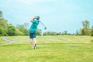 Man In Blue Swinging In Golf Course Wallpaper