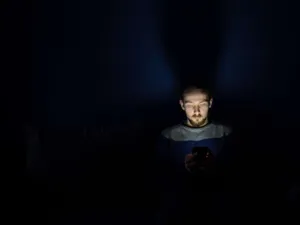 Man In Dark Room With Smartphone Addiction Wallpaper