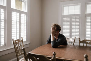 Man Sitting Alone In Dining Room Wallpaper