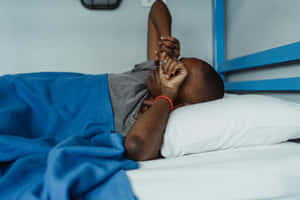 Man Sleeping In Bed Covered With Blue Blanket Wallpaper