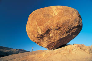 Man Standing Under Big Rock Wallpaper