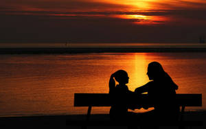 Mother And Daughter Bonding During Sunset Wallpaper