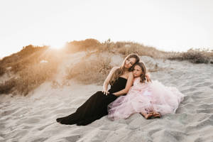 Mother And Daughter Sitting By The Beach Wallpaper