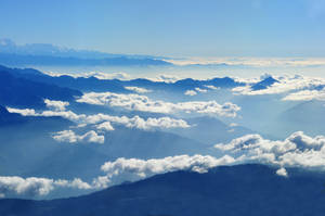 Mountains Reaching Into A Cloudy Sky Wallpaper