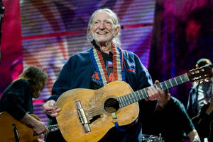 Musician Willie Nelson Smiling During Concert Wallpaper