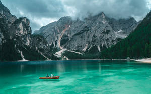 Natural Blue Lake With Boat Among Mountains Wallpaper