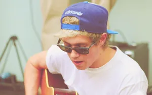 Niall Horan Cap Playing Guitar Wallpaper