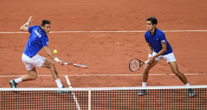 Nicolas Mahut Engaged In A Fierce Tennis Doubles Match Wallpaper