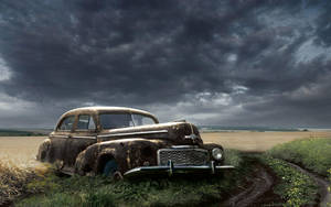 Nostalgic Remnant: Abandoned Old Car In Field Wallpaper