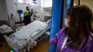 Nurse Looking Into Hospital Bed Wallpaper