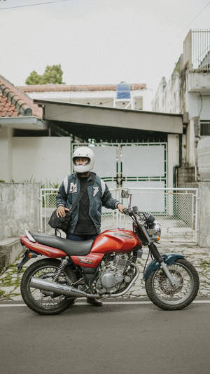 Passionate Bike Rider With His Dynamic Red Motorcycle Wallpaper