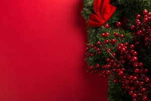Perfect For The Holiday Season: A Red Christmas Wreath Set Against A White Wall Wallpaper