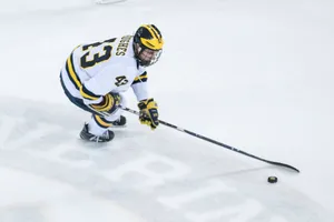 Quinn Hughes Leaning Forward While Dribbling Hockey Puck Wallpaper