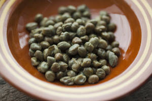 Scrumptious Dried Capers In A Rustic Brown Plate Wallpaper