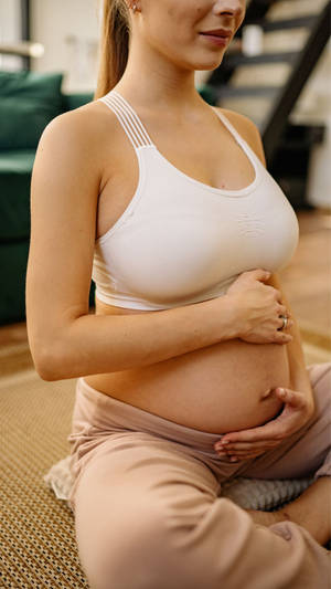 Serene Expectant Mother Lovingly Touching Her Baby Bump Wallpaper