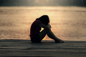 Serenity In Solitude: A Lone Girl Reflecting On A Dock Wallpaper