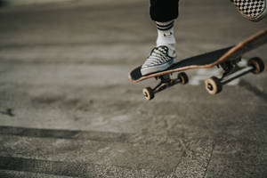 Skateboarder Expressing Style In Vans Checkered Shoes Wallpaper