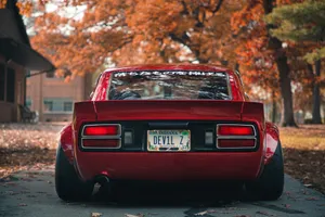 Sleek Red Datsun Car Parked On A City Street Wallpaper