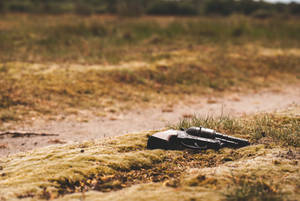 Solitary Revolver Resting On Rough Terrain Wallpaper