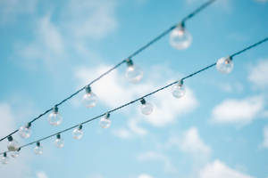 String Lights Under Blue Cloudy Sky Wallpaper