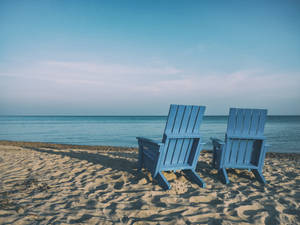 Take In The Ocean Views From The Comfort Of A Blue Beach Chair Wallpaper